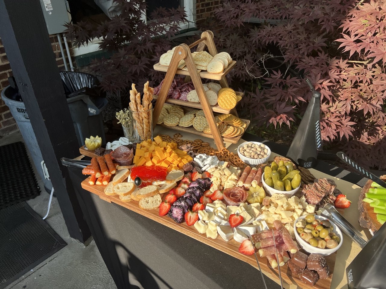 Large charcuterie board with cheeses, meats, pickles and a cracker tower