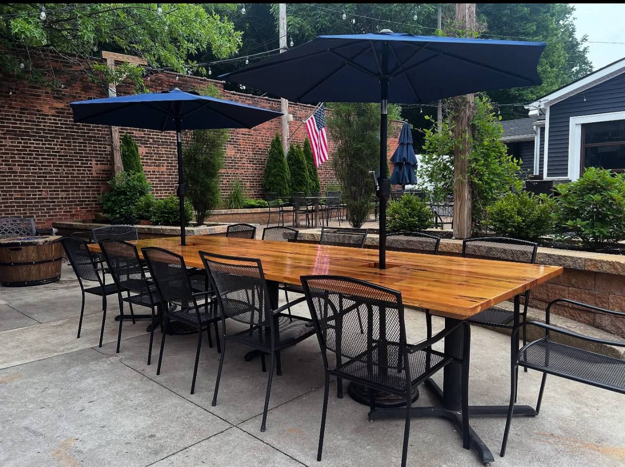 Long wood communal table with navy umbrellas on the patio