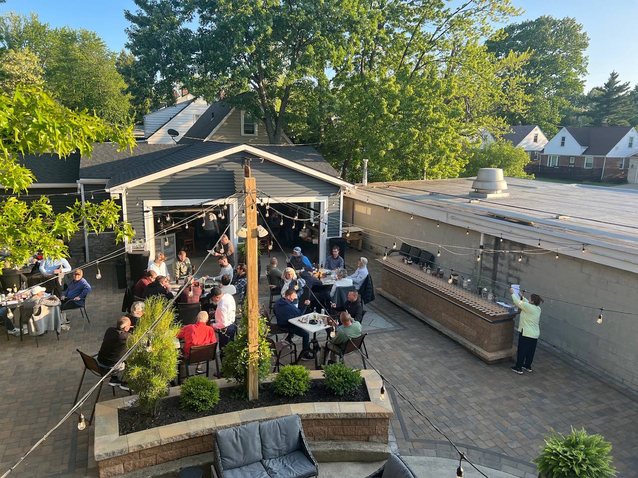 Back patio at golden hour with string lights and a full crowd
