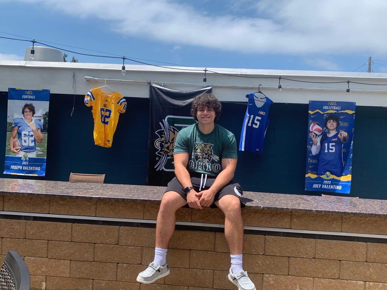 Local student athlete in front of banners for teams we sponsor