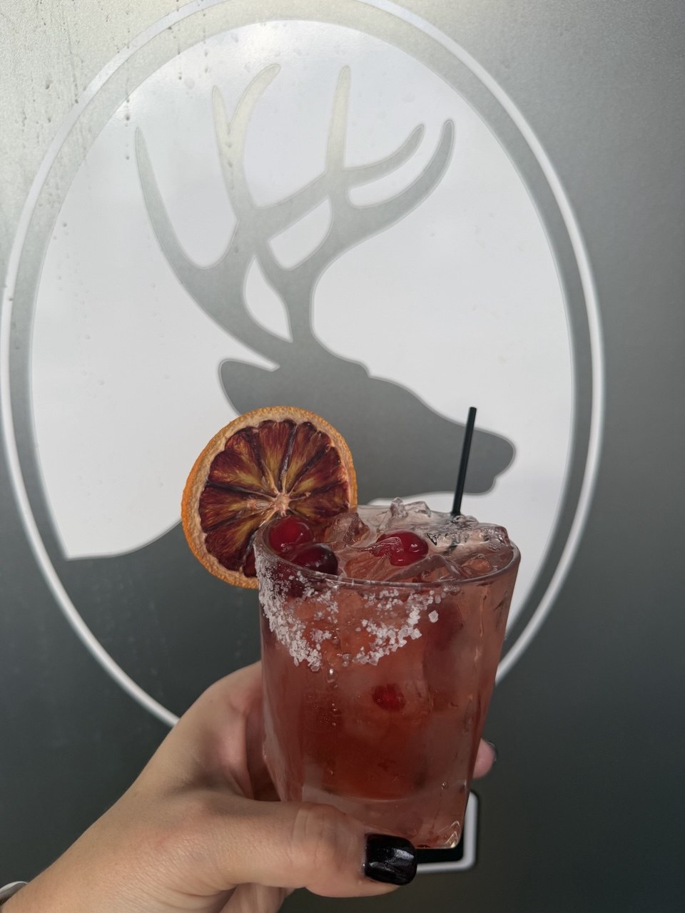 Red cocktail held up in front of the stag emblem